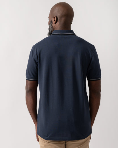 back shot of a model wearing a Fred Perry Mens Twin Tipped Signature Polo Shirt in Dark Airforce with Stockport Blue and Black trim