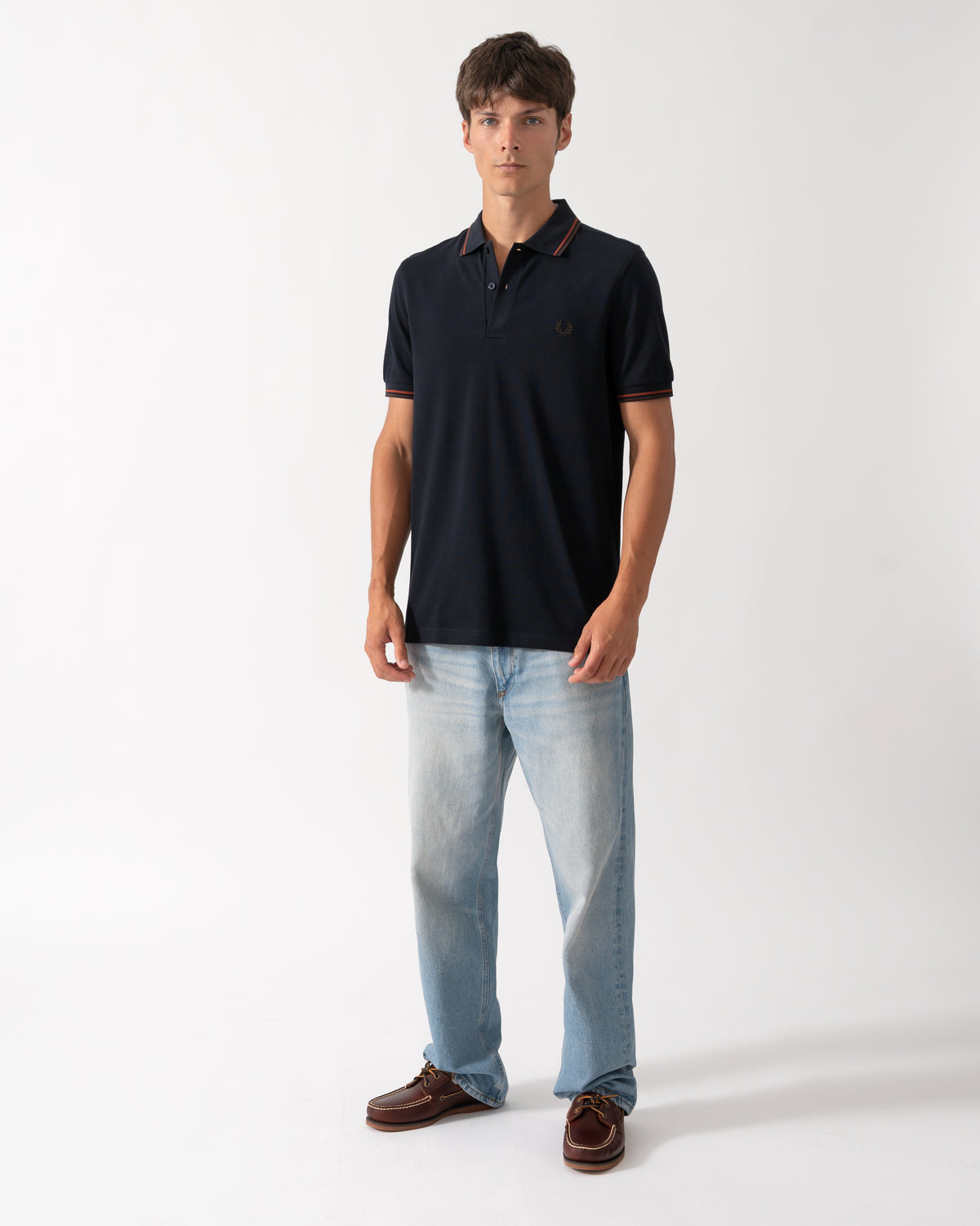 full length shot of a model wearing a Fred Perry Mens Twin Tipped Signature Polo Shirt in Navy with Burgundy and Rich brown trim