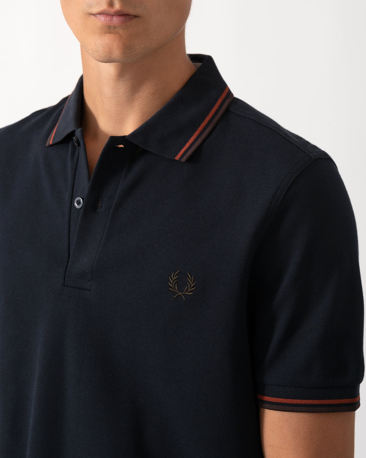 close up of a model wearing a Fred Perry Mens Twin Tipped Signature Polo Shirt in Navy with Burgundy and Rich brown trim