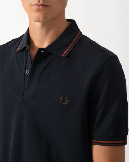 close up of a model wearing a Fred Perry Mens Twin Tipped Signature Polo Shirt in Navy with Burgundy and Rich brown trim