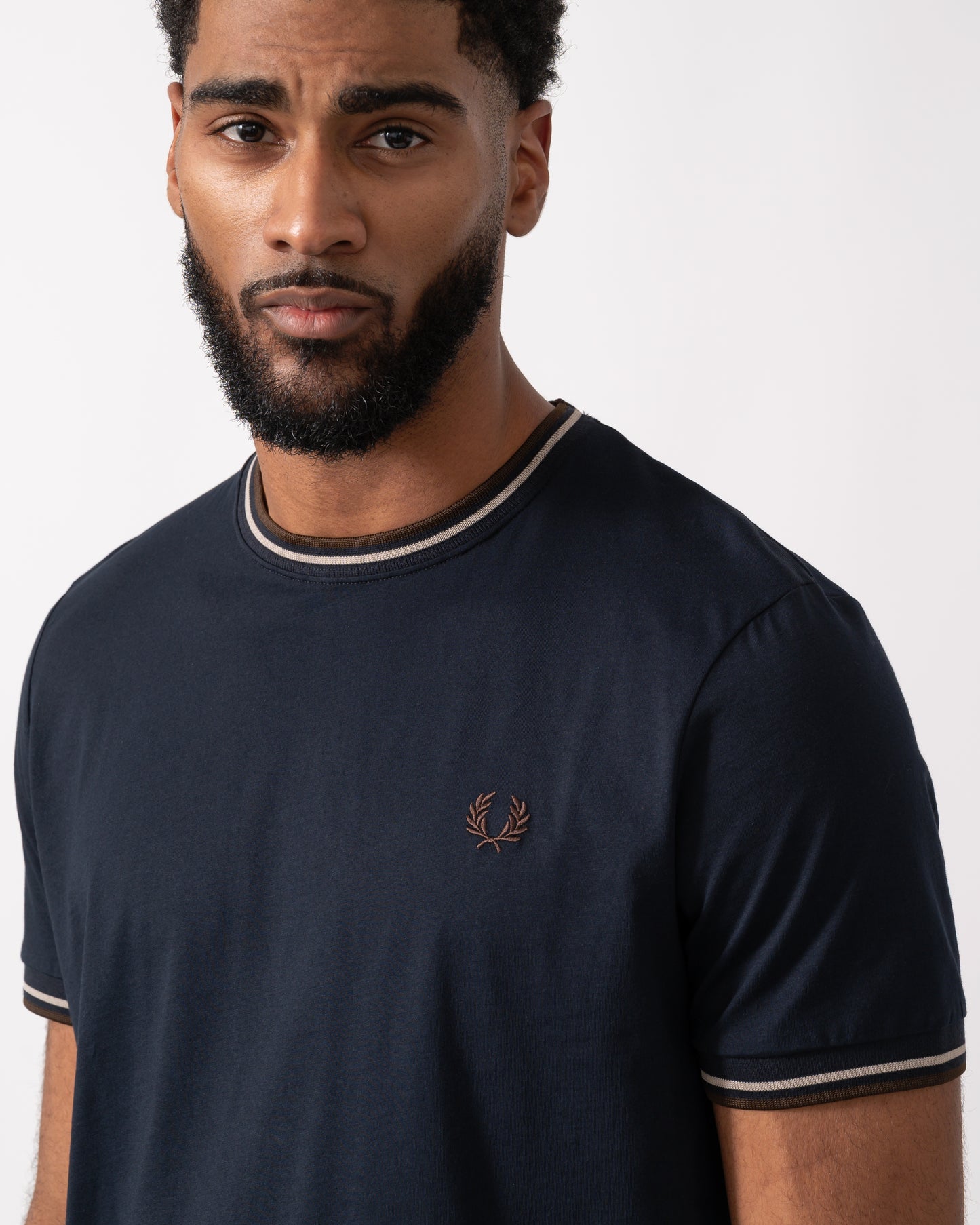close up of a Model wearing a Fred Perry Mens Twin Tipped T-Shirt  in Navy with Warm Oatmeal and Burnt Tobacco trim