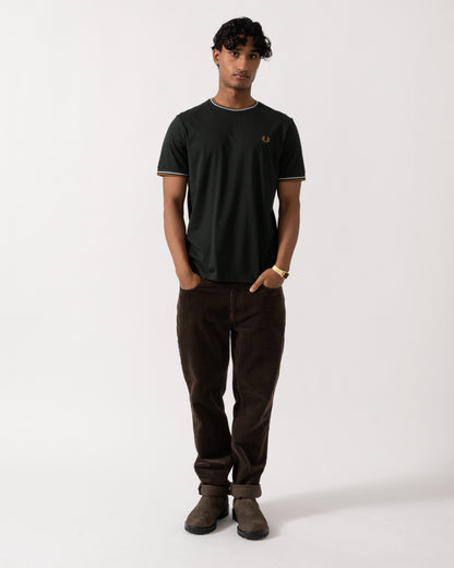 full length studio photograph of a model wearing a Fred Perry Mens Twin Tipped T-Shirt in Night Green with Dusk Blue and Dark Caramel trim 78C