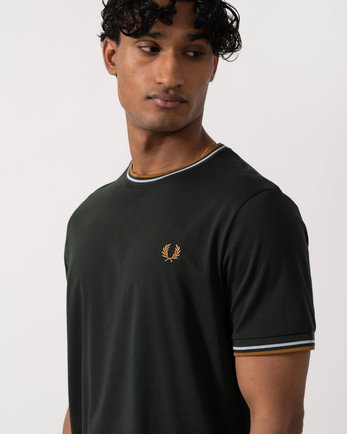 close up studio photograph of a model wearing a Fred Perry Mens Twin Tipped T-Shirt in Night Green with Dusk Blue and Dark Caramel trim 78C