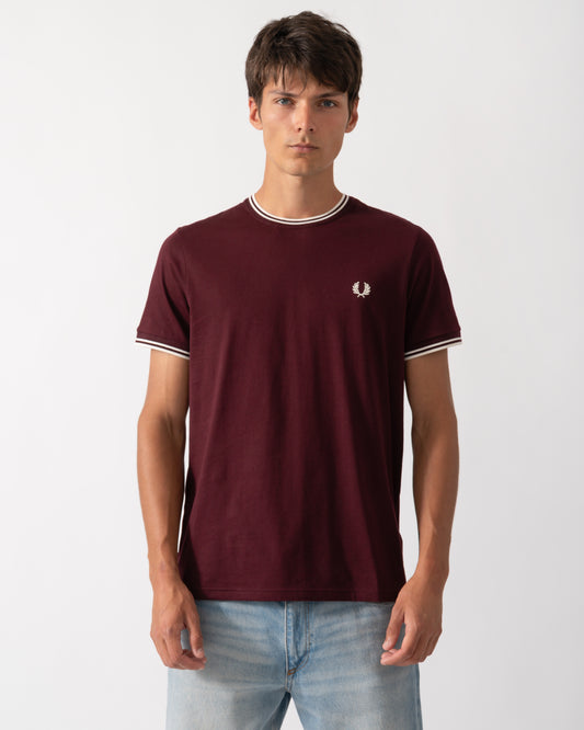 a model wearing a Fred Perry Mens Twin Tipped T-Shirt in Oxblood with Ecru trim
