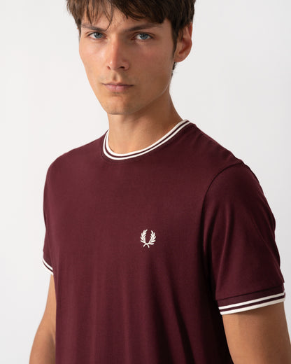 close up of a model wearing a Fred Perry Mens Twin Tipped T-Shirt in Oxblood with Ecru trim