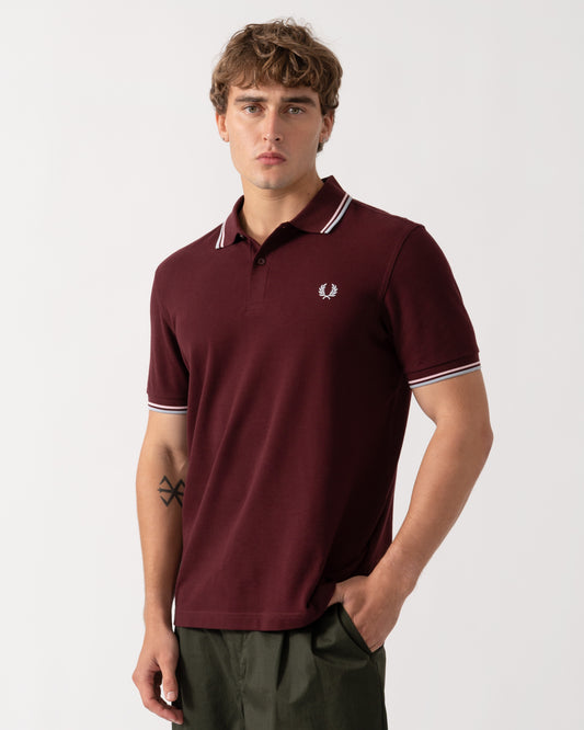 Model wearing Fred Perry Mens Twin Tipped Signature Polo Shirt - Oxblood/Iced Pink/Dusk Blue 83C