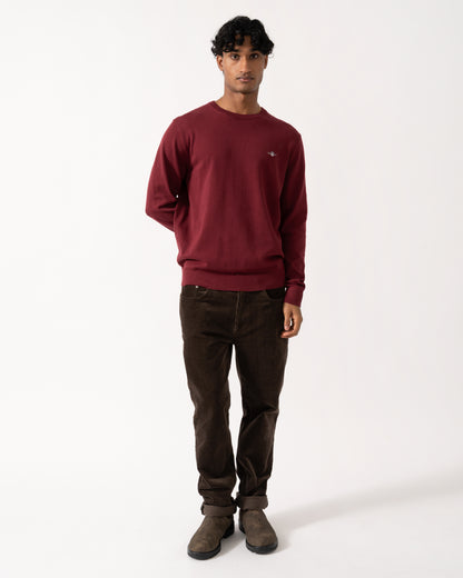 full length Studio photograph of a model wearing a GANT Mens Classic Cotton Shield Logo Crew Neck Jumper in 676 Deep Grape Wine