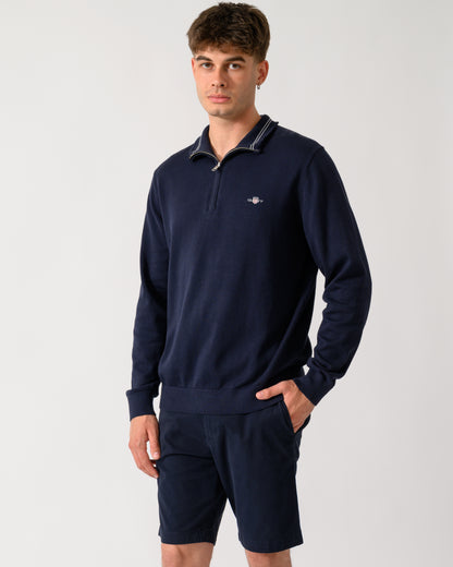 model wearing a GANT Mens Classic Cotton Shield Logo Half Zip Jumper n 433 Evening Blue