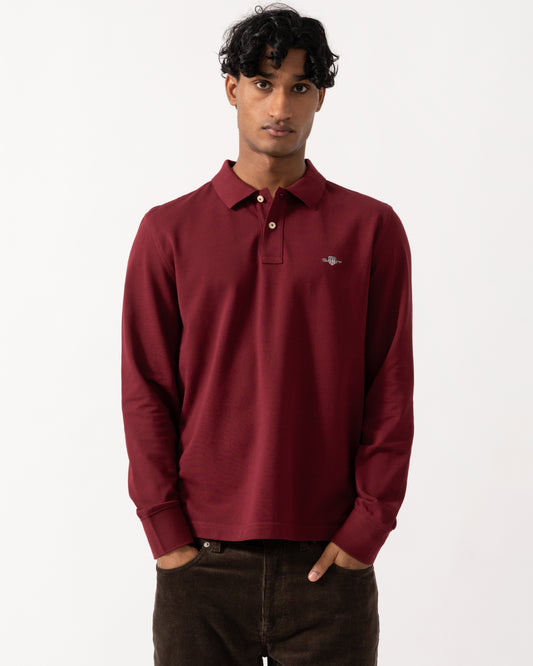 Studio photograph of a model wearing a GANT Mens Regular Fit Long Sleeve Shield Logo Pique Rugger in 676 Deep Grape Wine