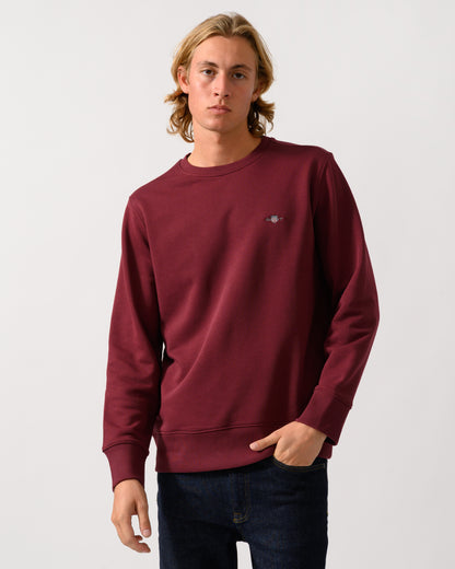 model wearing a GANT Mens Regular Fit Shield Logo Crew Neck Sweatshirt in 676 Deep Grape Wine