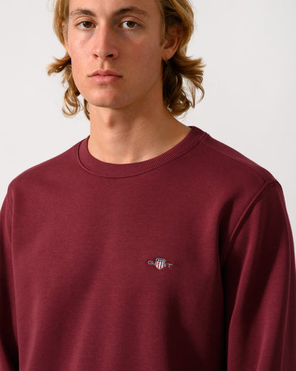 close up of model wearing a GANT Mens Regular Fit Shield Logo Crew Neck Sweatshirt in 676 Deep Grape Wine