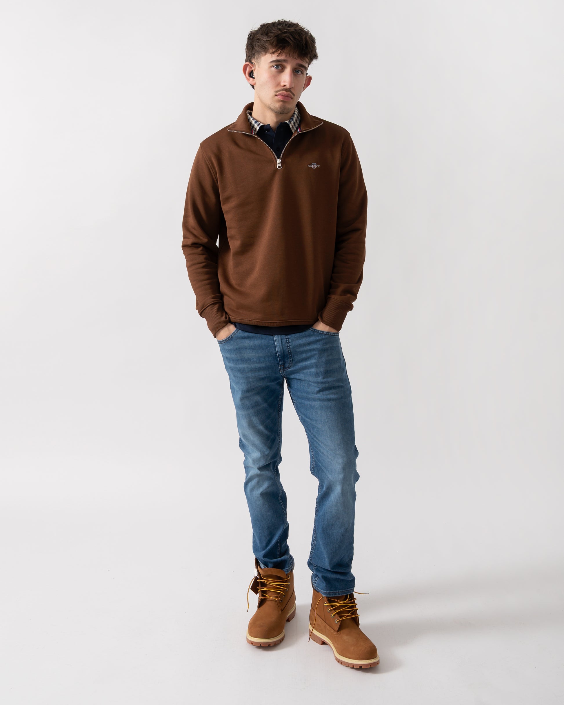 full length shot of a model wearing a GANT Mens Regular Fit Shield Logo Half Zip Sweatshirt in 229 Mahogany Brown
