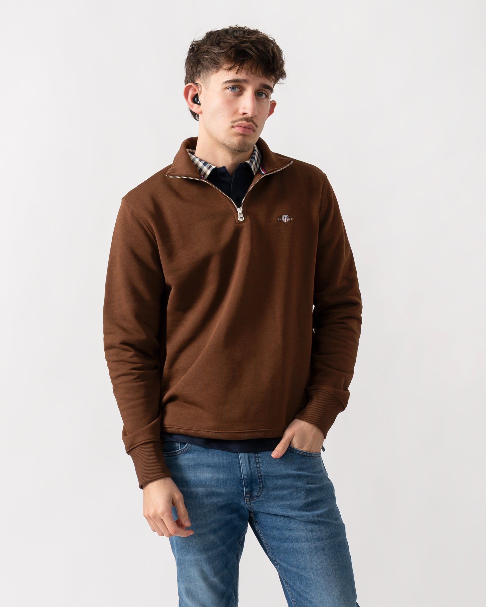 studio shot of a model wearing a GANT Mens Regular Fit Shield Logo Half Zip Sweatshirt in 229 Mahogany Brown