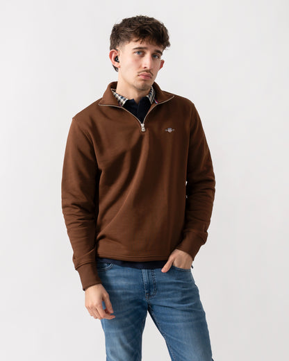 studio shot of a model wearing a GANT Mens Regular Fit Shield Logo Half Zip Sweatshirt in 229 Mahogany Brown