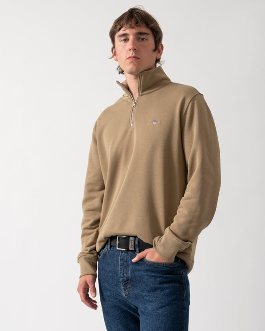 model wearing a GANT Mens Regular Fit Shield Logo Half Zip Sweatshirt in 264 Light Taupe