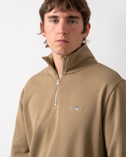 close up shot of a model wearing a GANT Mens Regular Fit Shield Logo Half Zip Sweatshirt in 264 Light Taupe