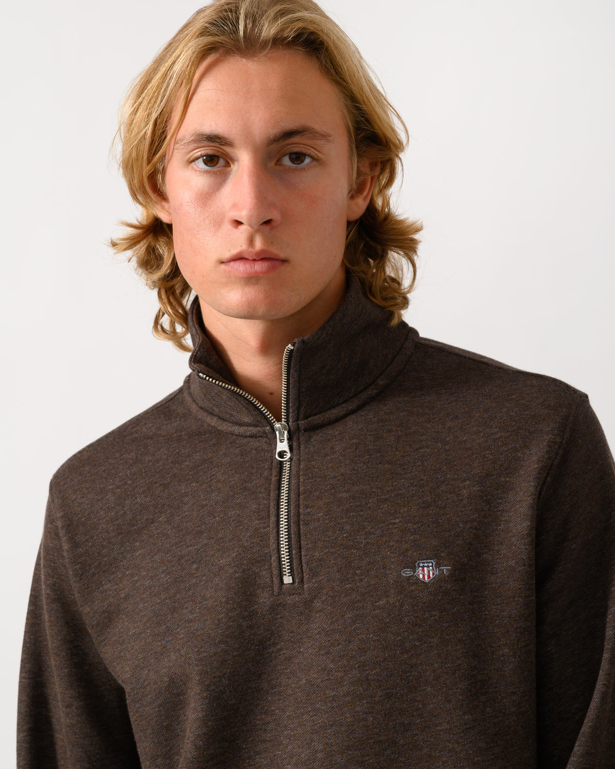 close up of a model wearing a GANT Mens Regular Fit Shield Logo Half Zip Sweatshirt in 284 Black Brown Melange