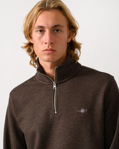 close up of a model wearing a GANT Mens Regular Fit Shield Logo Half Zip Sweatshirt in 284 Black Brown Melange