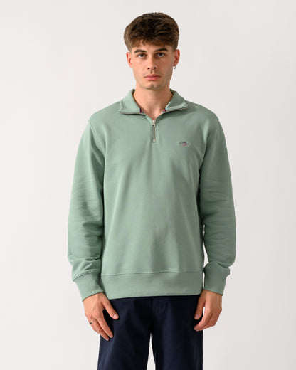 model wearing a GANT Mens Regular Fit Shield Logo Half Zip Sweatshirt in 308 Surplus Mint