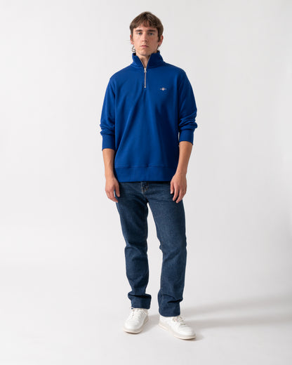 full length of model wearing a GANT Mens Regular Fit Shield Logo Half Zip Sweatshirt in 435 Crisp Blue