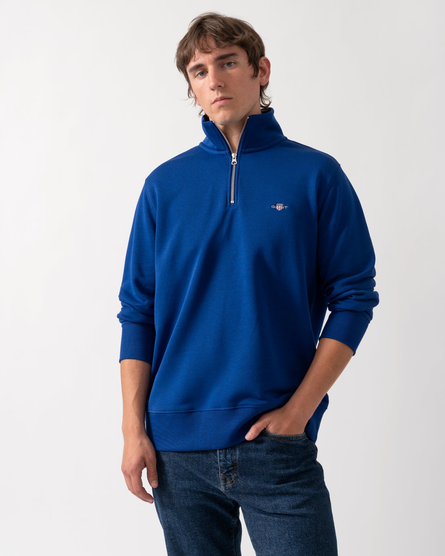 model wearing a GANT Mens Regular Fit Shield Logo Half Zip Sweatshirt in 435 Crisp Blue