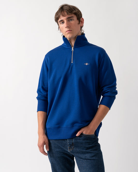 model wearing a GANT Mens Regular Fit Shield Logo Half Zip Sweatshirt in 435 Crisp Blue