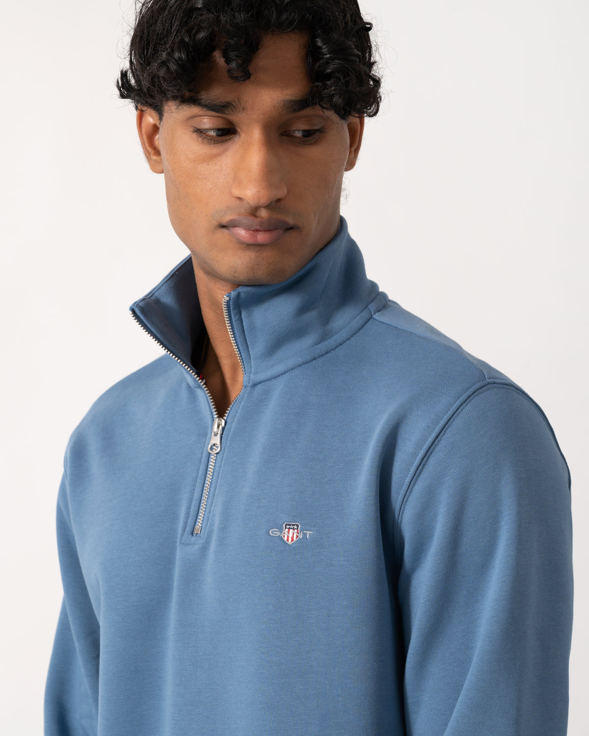 close up Studio photograph of a model wearing a GANT Mens Regular Fit Shield Logo Half Zip Sweatshirt in 476 Blue Horizon