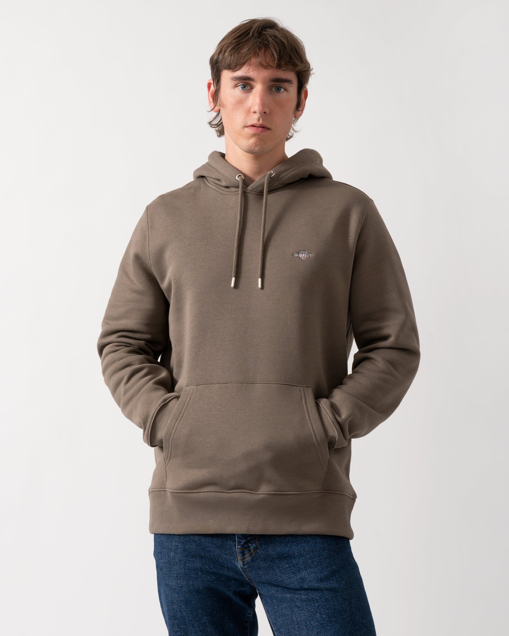 model wearing a GANT Mens Regular Fit Shield Logo Pullover Hoodie in 260 Faded Taupe