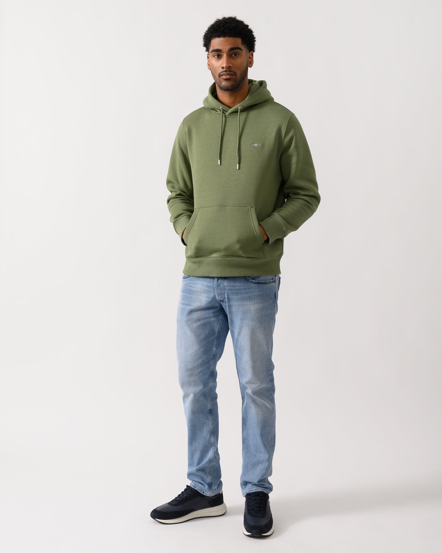 full length shot of a model wearing a GANT Mens Regular Fit Shield Logo Pullover Hoodie in 379 Dry Herb Green