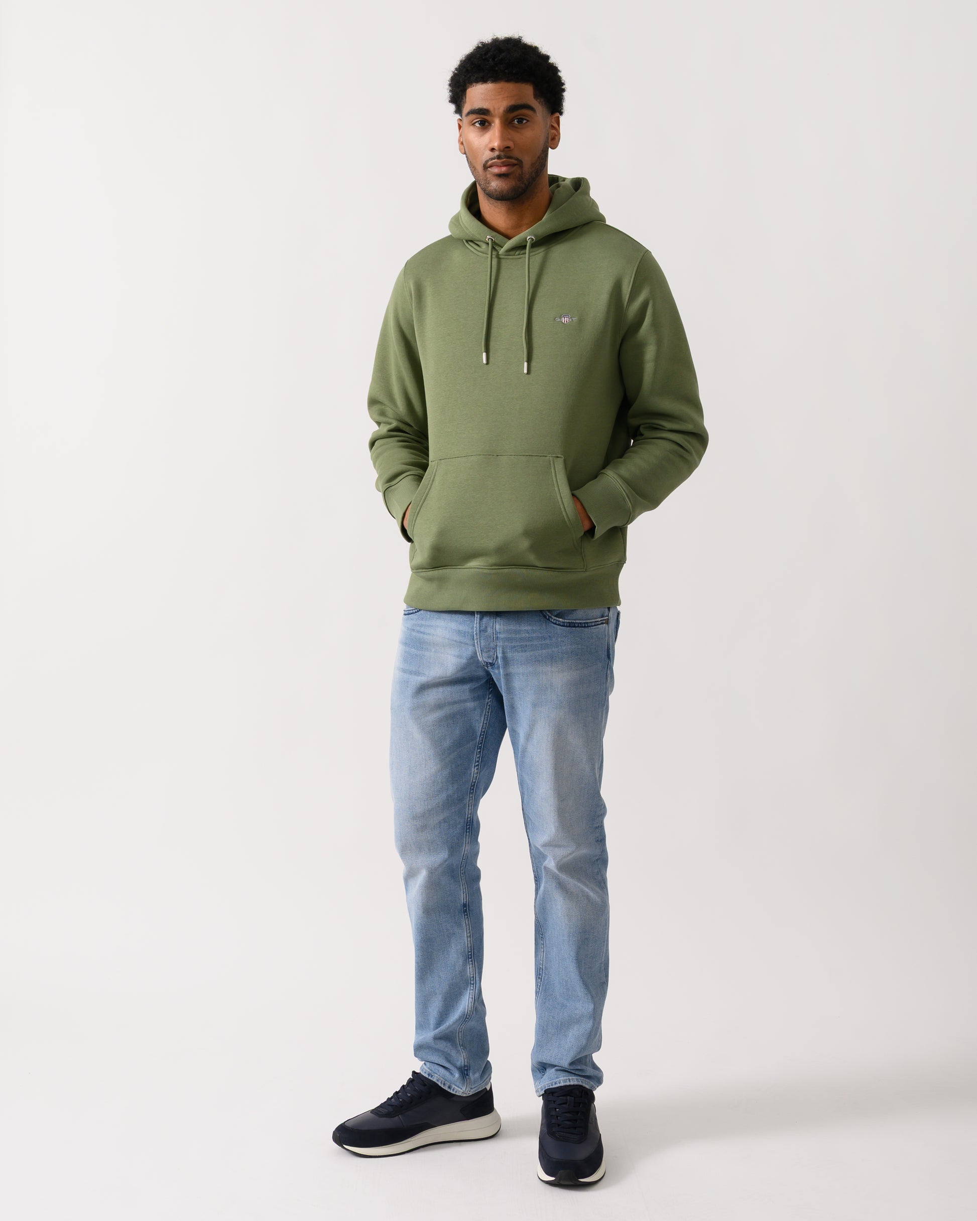 full length shot of a model wearing a GANT Mens Regular Fit Shield Logo Pullover Hoodie in 379 Dry Herb Green