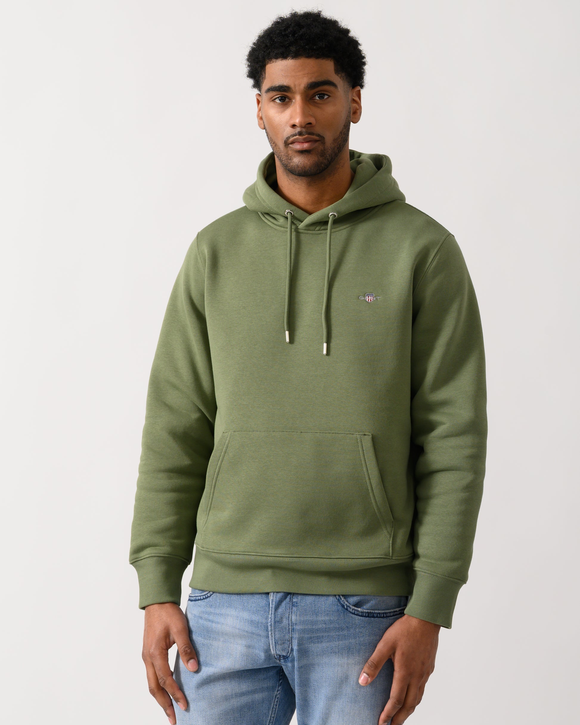 model wearing a GANT Mens Regular Fit Shield Logo Pullover Hoodie in 379 Dry Herb Green