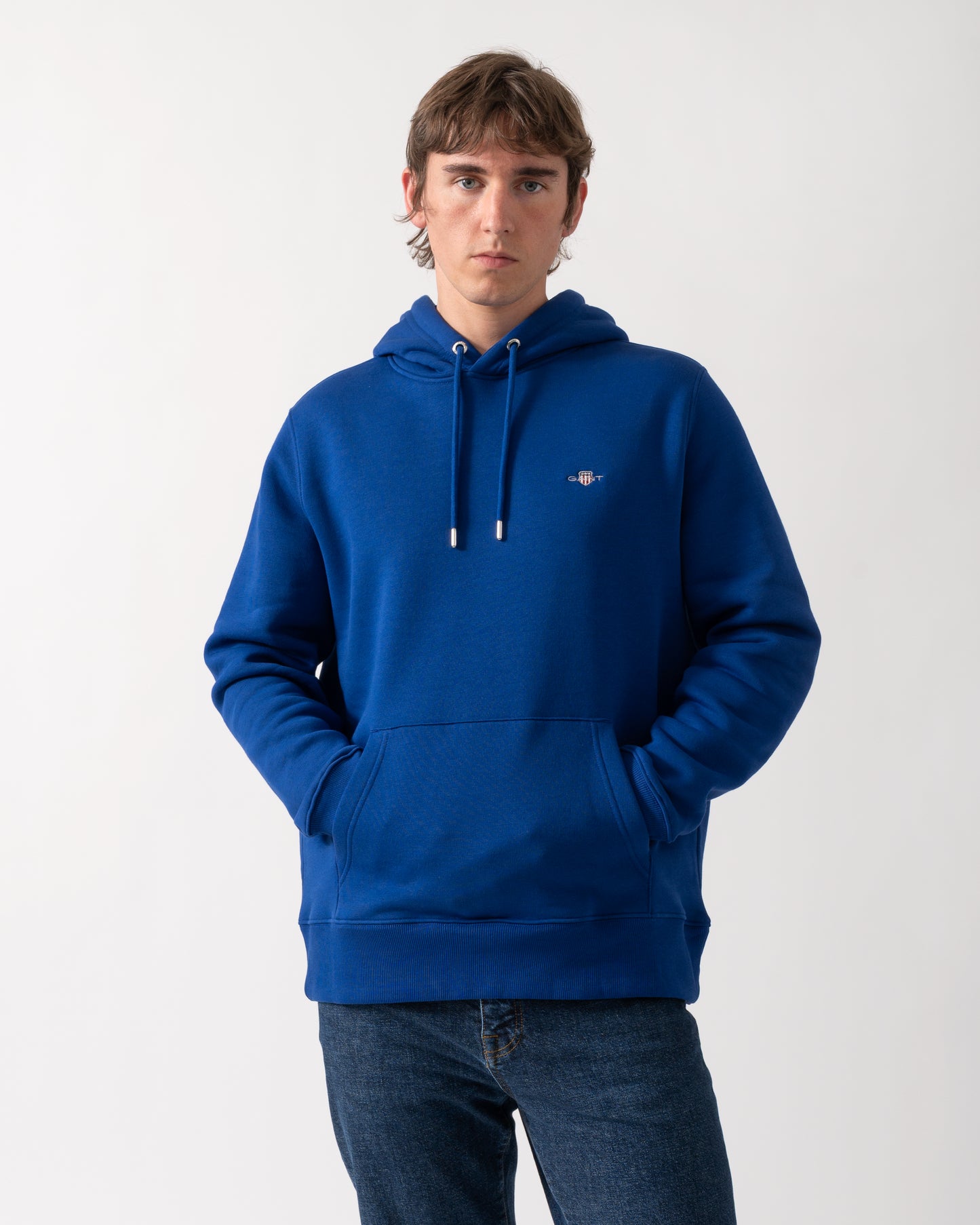 model wearing a GANT Mens Regular Fit Shield Logo Pullover Hoodie in 435 Crisp Blue