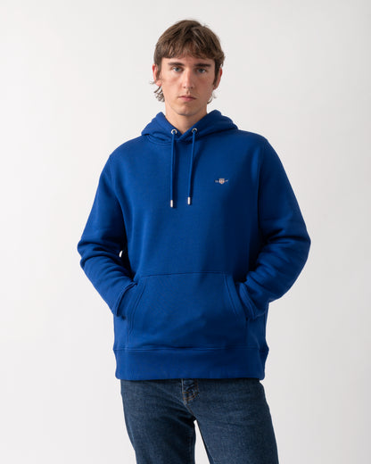 model wearing a GANT Mens Regular Fit Shield Logo Pullover Hoodie in 435 Crisp Blue
