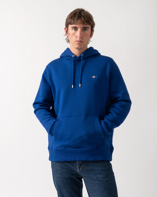 model wearing a GANT Mens Regular Fit Shield Logo Pullover Hoodie in 435 Crisp Blue