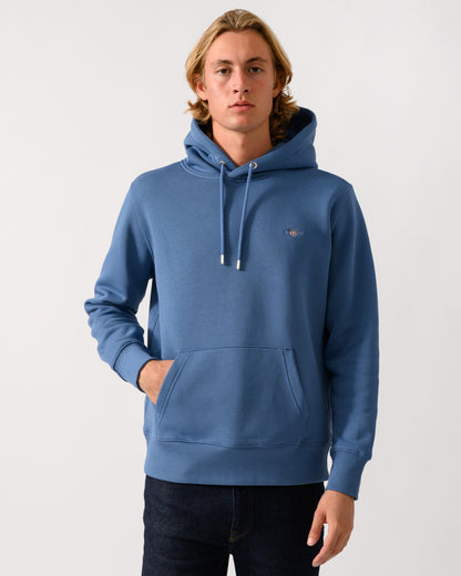 model wearing a GANT Mens Regular Fit Shield Logo Pullover Hoodie in 476 Blue Horizon