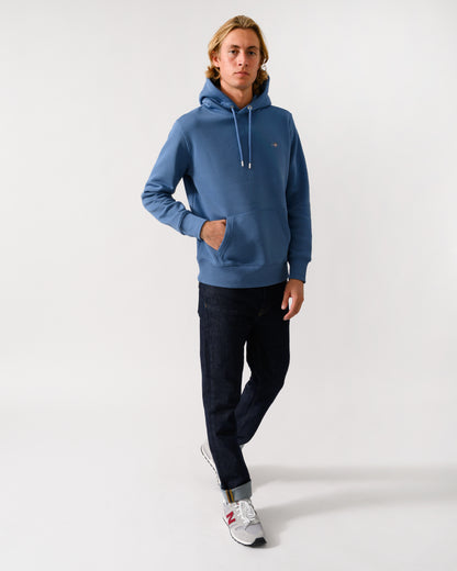 full length of a model wearing a GANT Mens Regular Fit Shield Logo Pullover Hoodie in 476 Blue Horizon