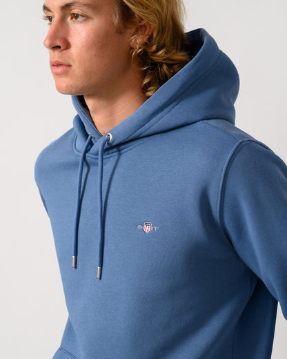 close up of a model wearing a GANT Mens Regular Fit Shield Logo Pullover Hoodie in 476 Blue Horizon