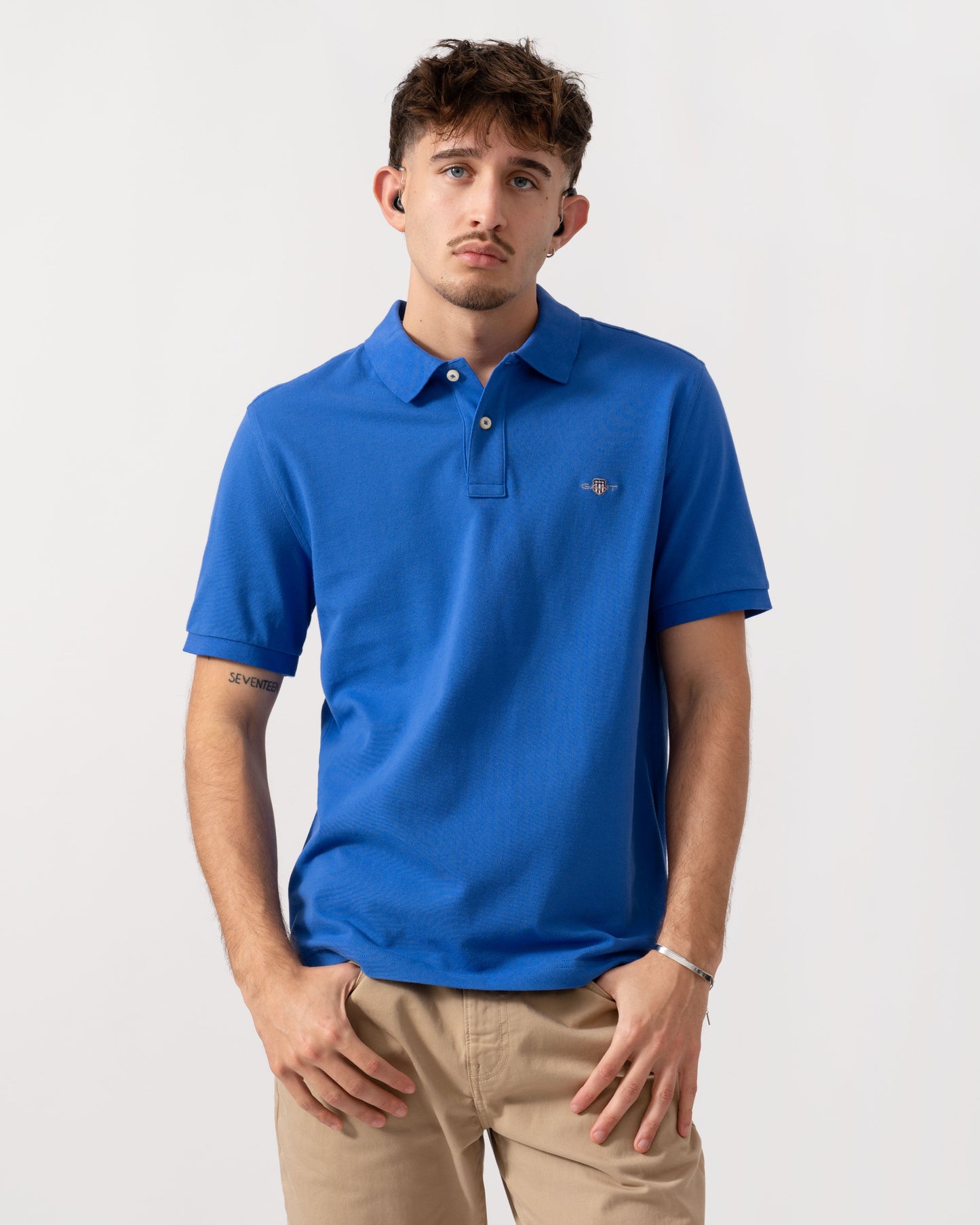 Model wearing a GANT Mens Regular Fit Short Sleeve Shield Logo Pique Polo in Royal Blue