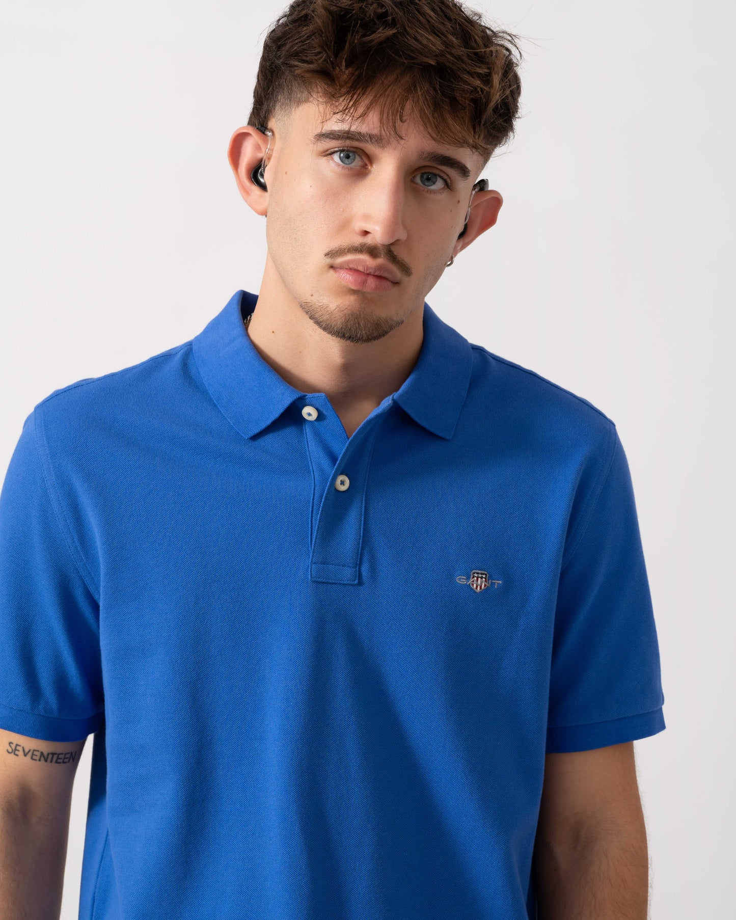 close up of a Model wearing a GANT Mens Regular Fit Short Sleeve Shield Logo Pique Polo in Royal Blue