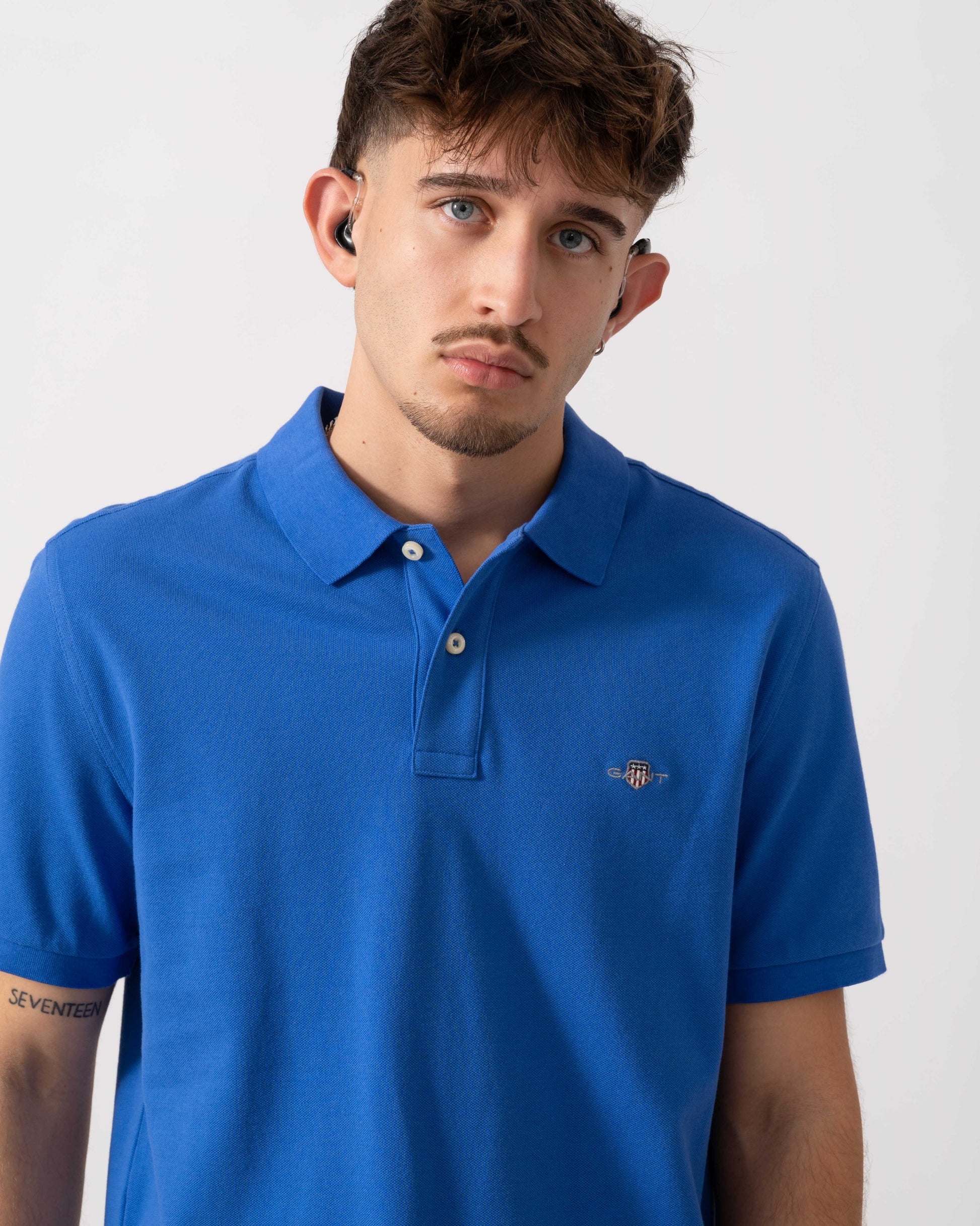 close up of a Model wearing a GANT Mens Regular Fit Short Sleeve Shield Logo Pique Polo in Royal Blue