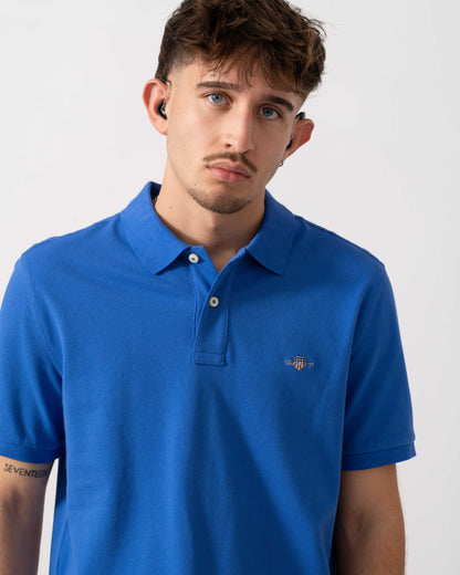 close up of a Model wearing a GANT Mens Regular Fit Short Sleeve Shield Logo Pique Polo in Royal Blue