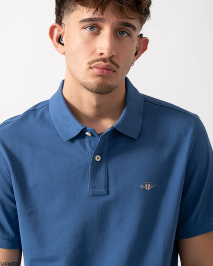 close up shot of a Model wearing a GANT Mens Regular Fit Short Sleeve Shield Logo Pique Polo in Vintage Blue