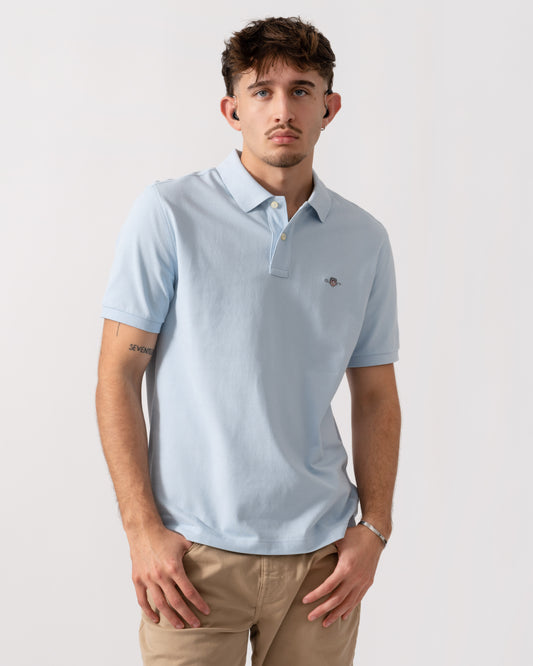 model wearing a GANT Mens Regular Fit Short Sleeve Shield Logo Pique Polo in Fresh Blue