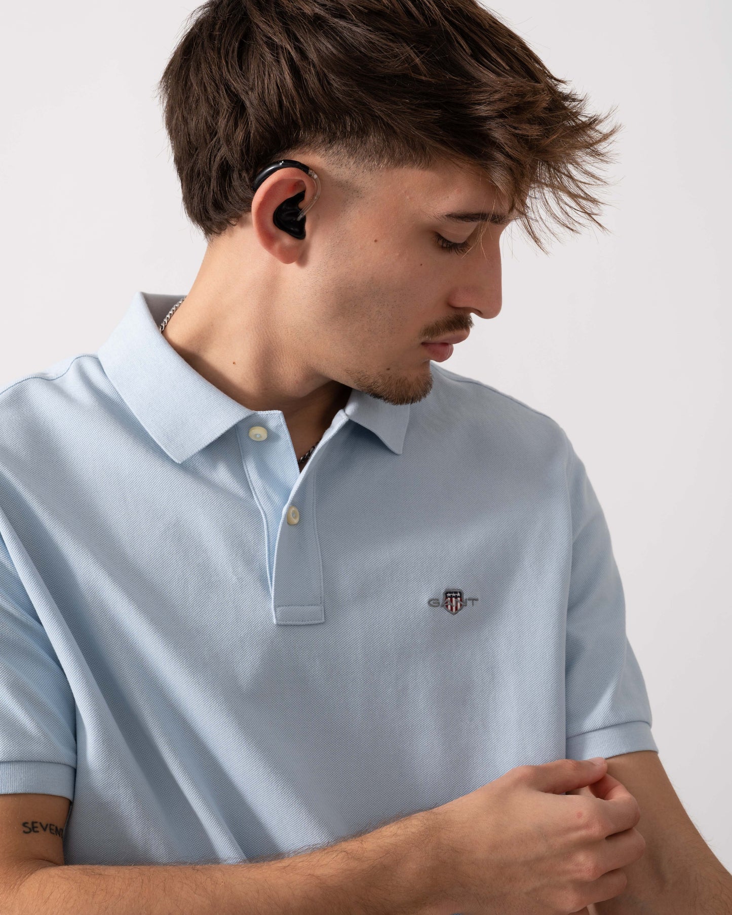 detail shot of a model wearing a GANT Mens Regular Fit Short Sleeve Shield Logo Pique Polo in Fresh Blue