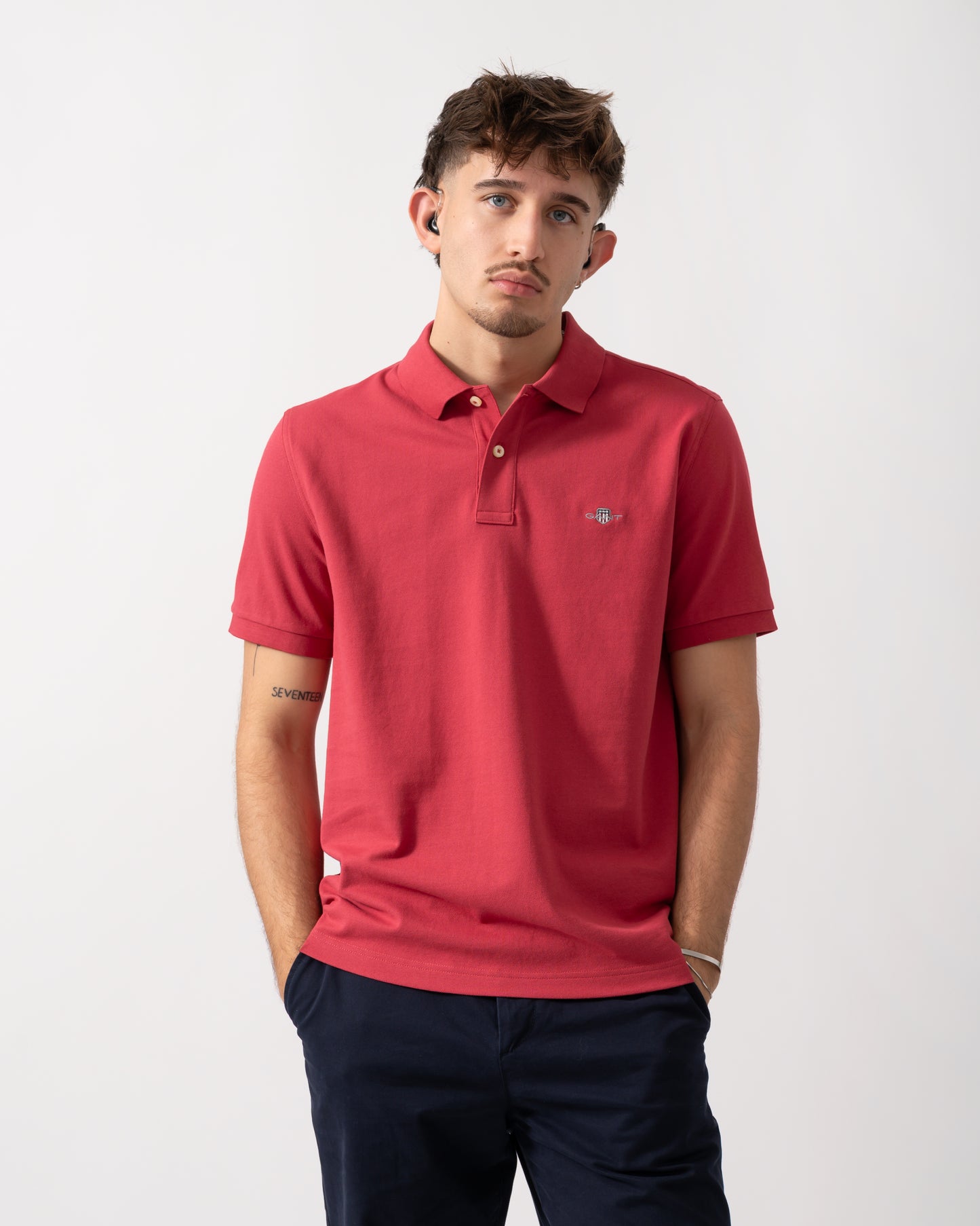 Model wearing a GANT Mens Regular Fit Short Sleeve Shield Logo Pique Polo in Muted Red