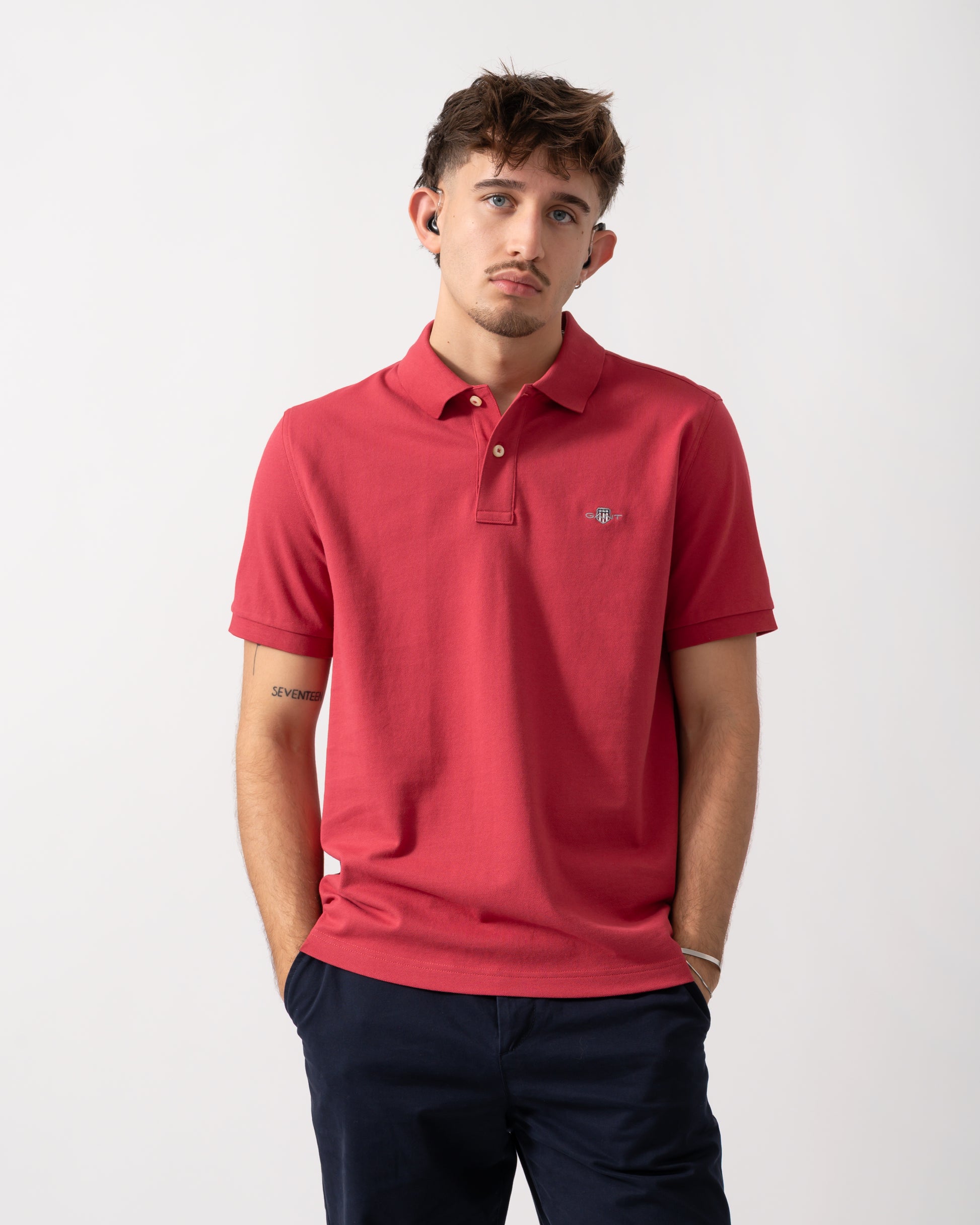 Model wearing a GANT Mens Regular Fit Short Sleeve Shield Logo Pique Polo in Muted Red