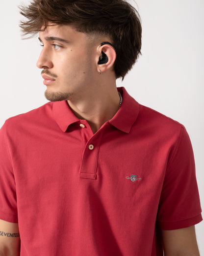 detail shot of a Model wearing a GANT Mens Regular Fit Short Sleeve Shield Logo Pique Polo in Muted Red