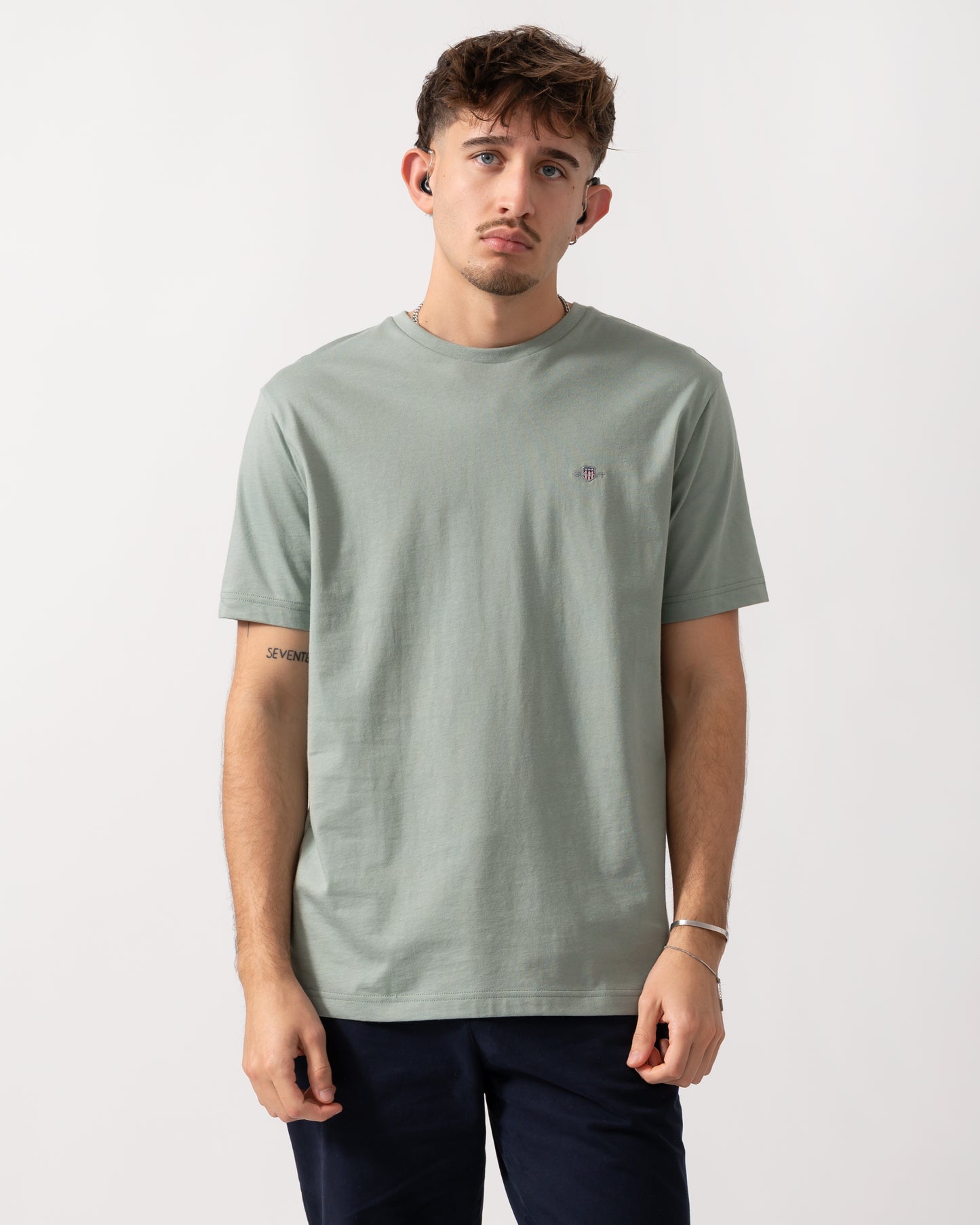 Model wearing a GANT Mens Regular Fit Short Sleeve Shield Logo T-Shirt in Ceramic Grey