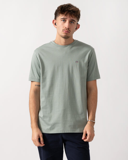 Model wearing a GANT Mens Regular Fit Short Sleeve Shield Logo T-Shirt in Ceramic Grey