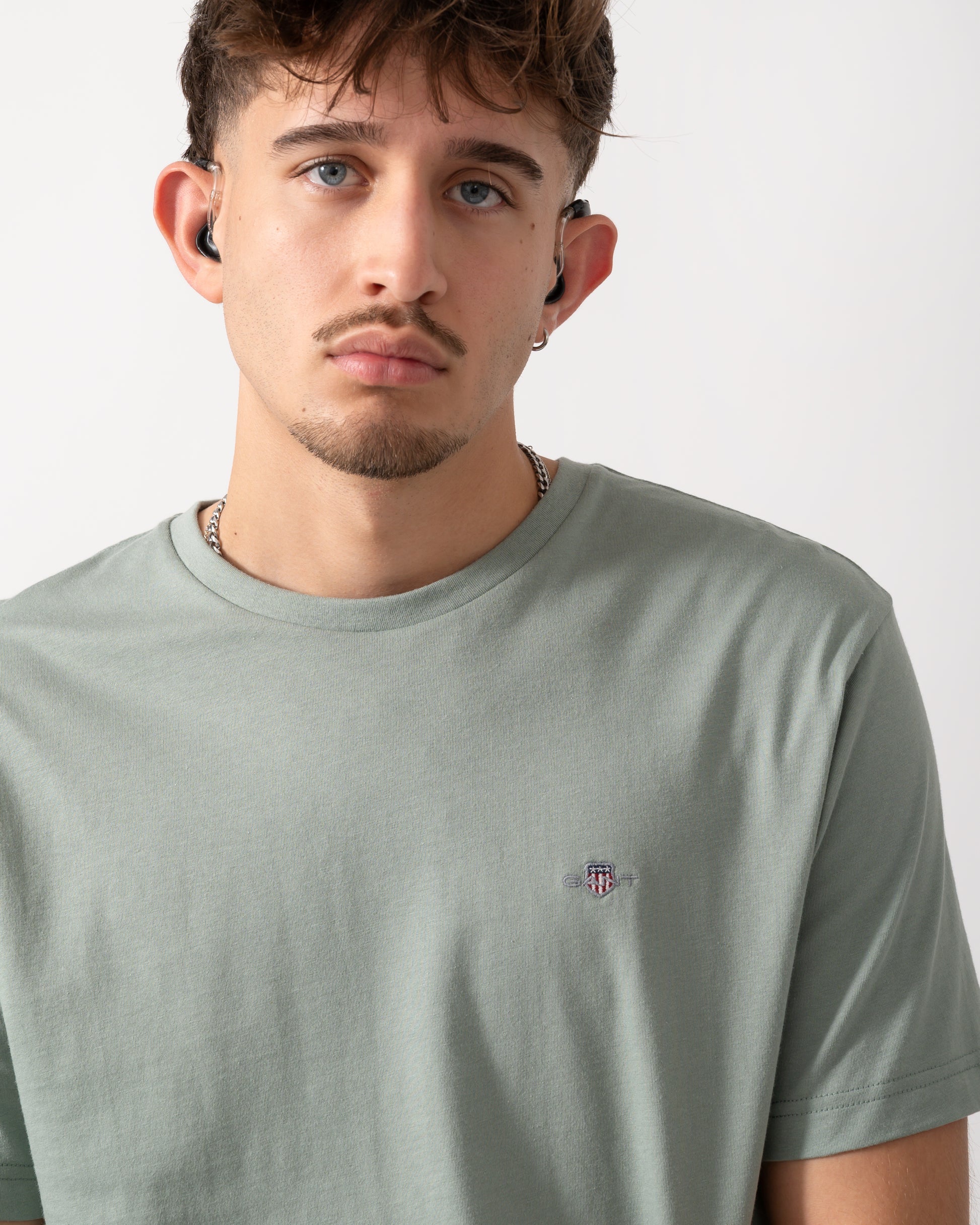 Close up shot of a Model wearing a GANT Mens Regular Fit Short Sleeve Shield Logo T-Shirt in Ceramic Grey